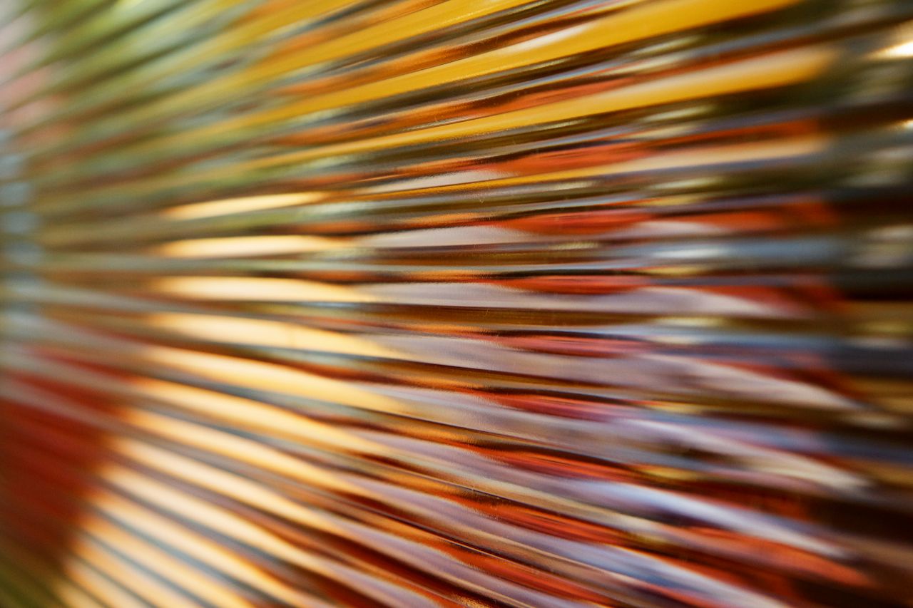 Abstract blurred image of diagonal colored stripes in orange, yellow, red and blue tones, vibrant and energetic mood